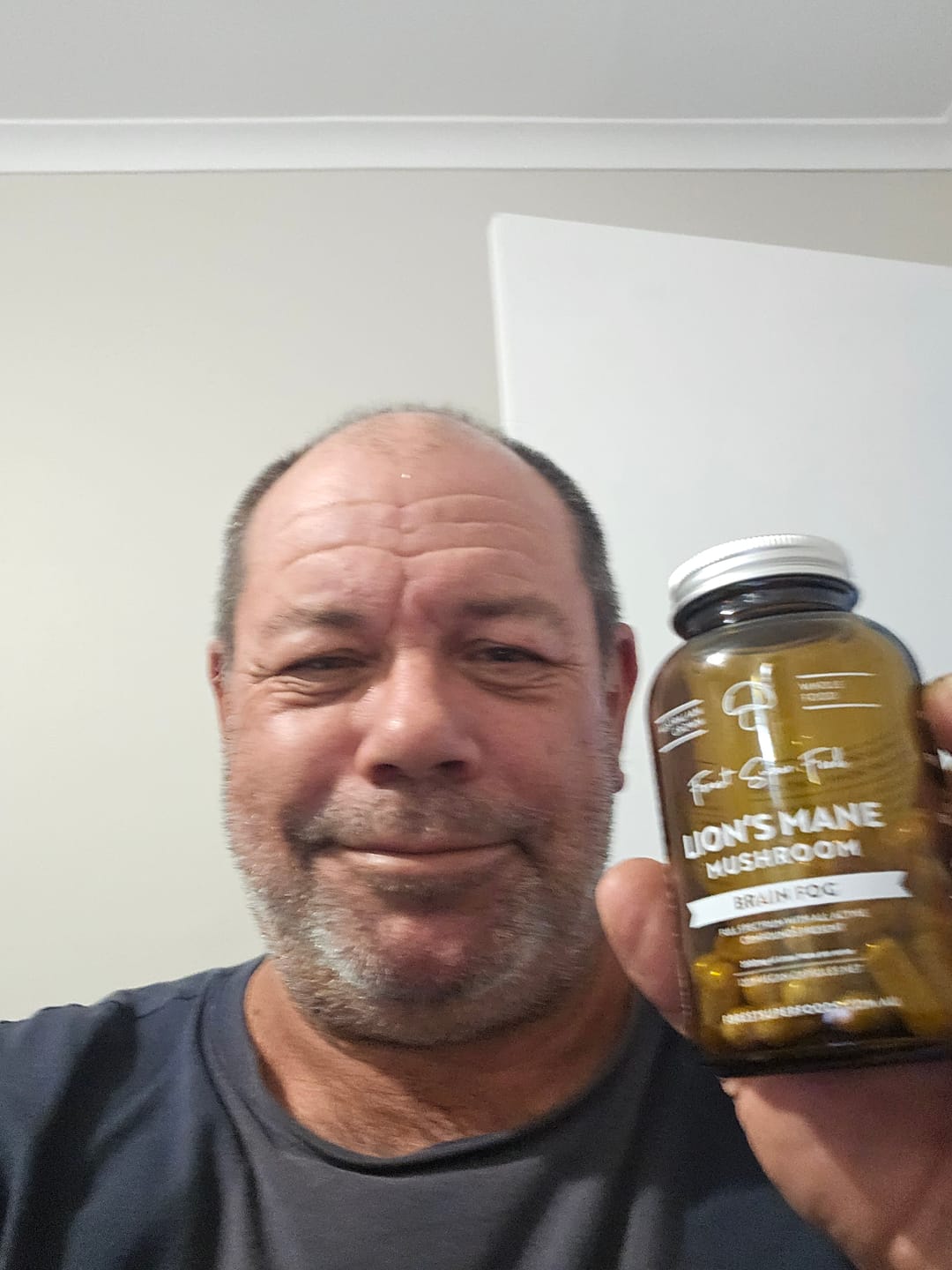 Customer holding a bottle of Lions Mane Mushroom Capsules, sharing how it helped improve clarity and focus throughout the day.